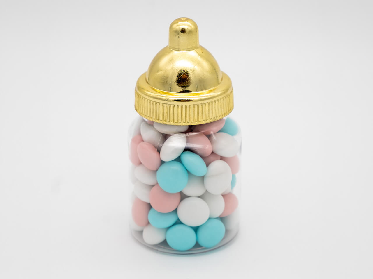 Babyflesje met blauwe, roze en witte chocoladedragees en een goudkleurige dop